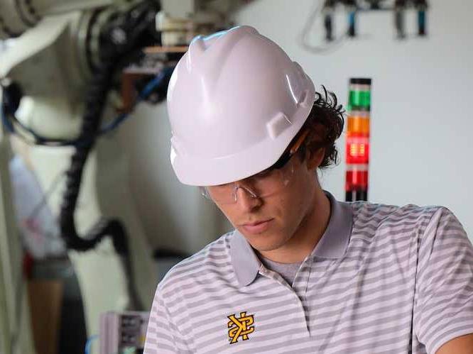 man with safety goggles and hard hat on focusing on project